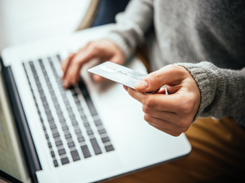 Person betaler med kreditkort på en computer.