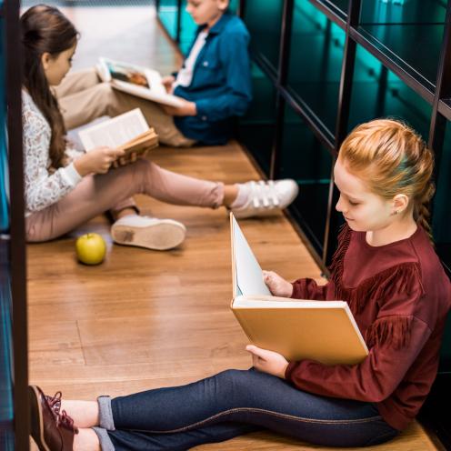 Elever læser bøger. Skoleklasse på biblioteket.