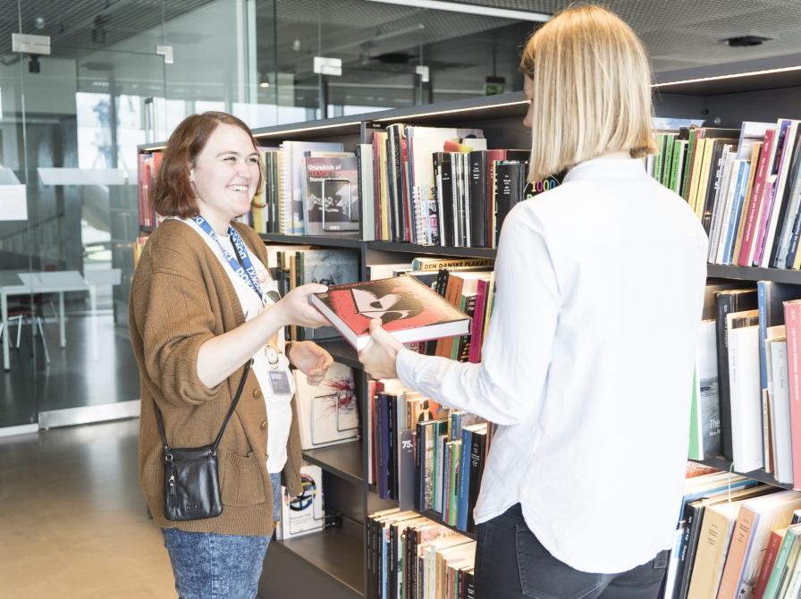 Bibliotekar anbefaler bog til borger.