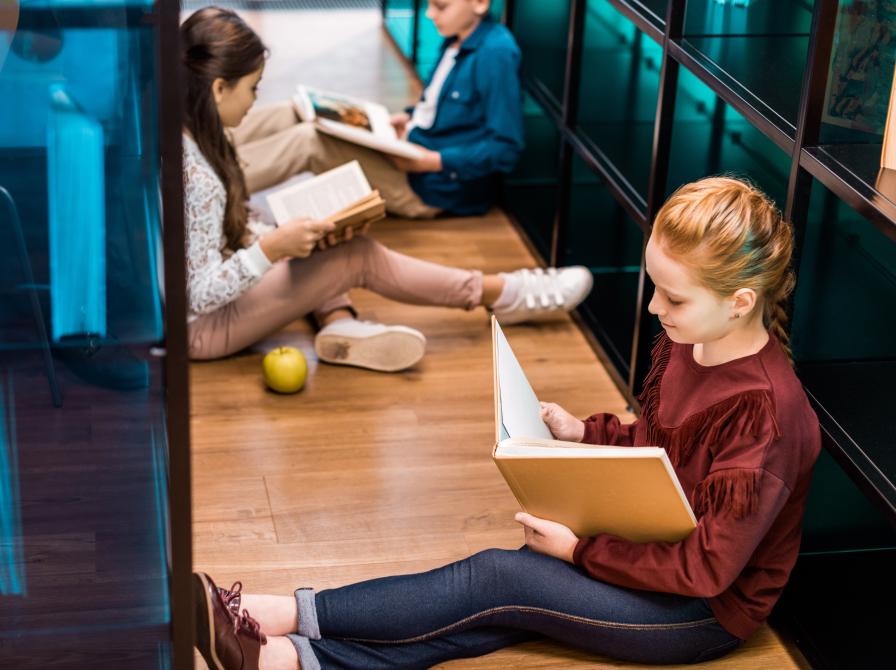 Elever læser bøger. Skoleklasse på biblioteket.